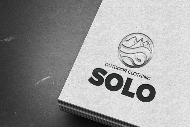 Realizzazione grafica Logo Solo pittogramma a cerchio nel quale è inserito un occhio e il profilo di una montagna con font bold del naming SOLO e pay-out Outdoor Clothing su fondo bianco